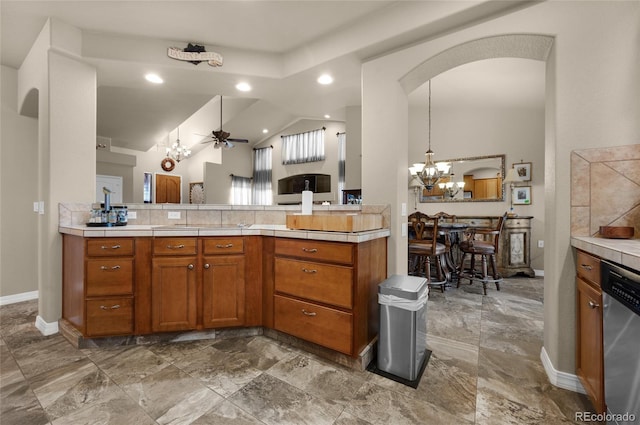 kitchen with dishwasher, ceiling fan with notable chandelier, kitchen peninsula, and vaulted ceiling