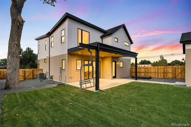 back house at dusk featuring cooling unit, a yard, and a patio area