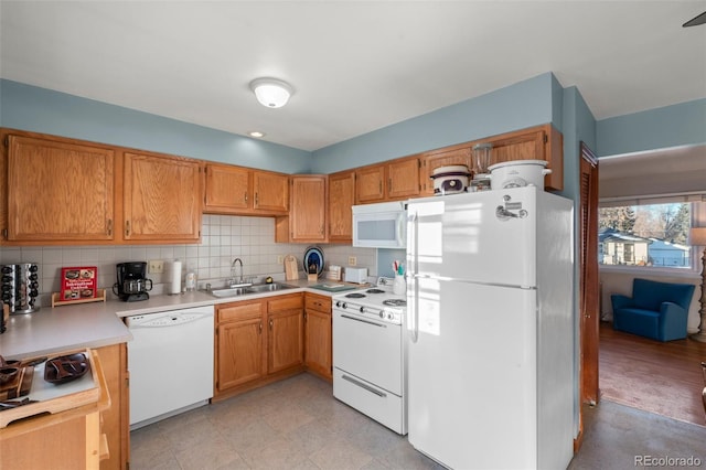 kitchen featuring white appliances, sink, and backsplash