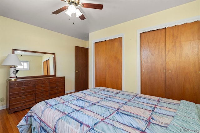 bedroom with multiple closets, wood-type flooring, and ceiling fan