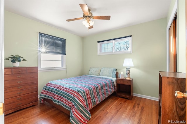 bedroom featuring multiple windows, light hardwood / wood-style floors, a closet, and ceiling fan