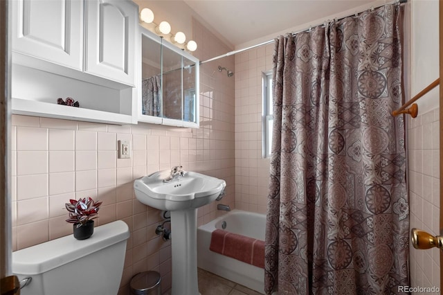 bathroom with tile patterned flooring, tile walls, shower / bathtub combination with curtain, and toilet