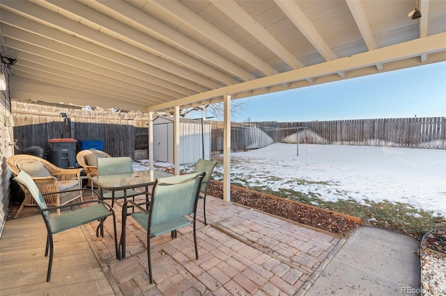 snow covered patio with a storage unit