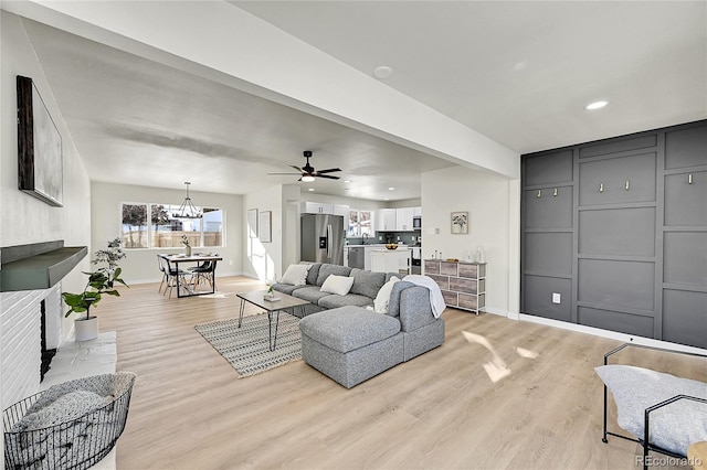 living room featuring ceiling fan with notable chandelier and light hardwood / wood-style floors