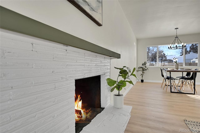 room details with wood-type flooring, an inviting chandelier, and a fireplace