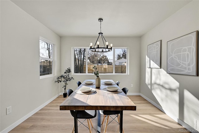 dining area with a healthy amount of sunlight, a notable chandelier, and light hardwood / wood-style floors