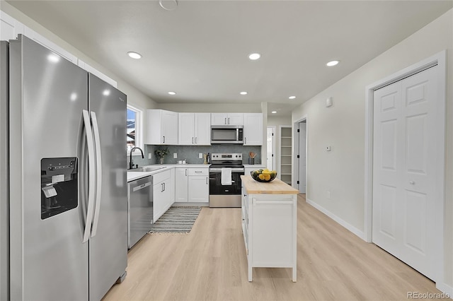 kitchen featuring white cabinets, butcher block counters, stainless steel appliances, decorative backsplash, and sink