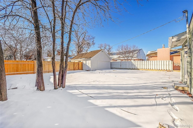 yard covered in snow with a garage and an outdoor structure