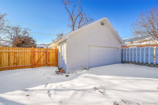 view of snowy exterior featuring a garage and an outdoor structure