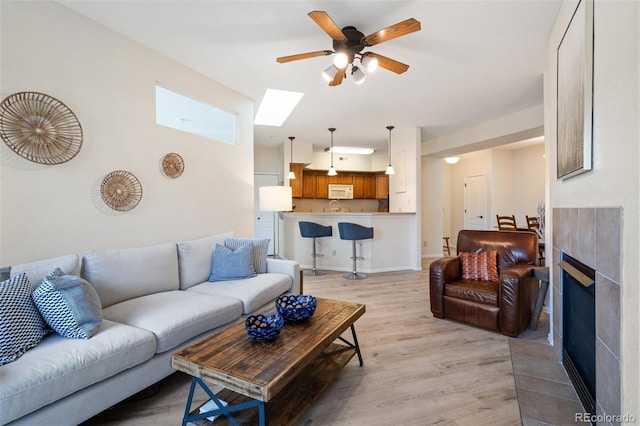 1816 Montura Vw Unit 204, Colorado Springs, CO 80919 - living area featuring a ceiling fan, a tile fireplace, and light wood finished floors