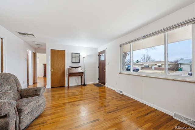 living area with baseboards, visible vents, and light wood-type flooring