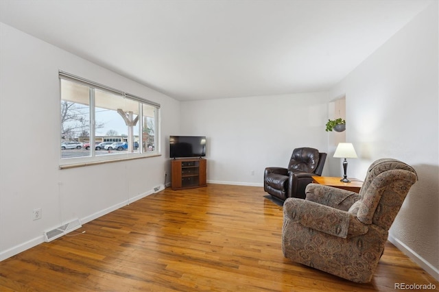 living area with visible vents, baseboards, and wood-type flooring