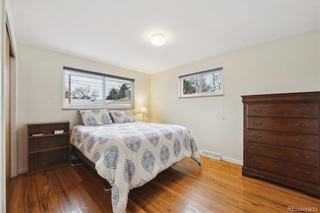 bedroom with wood finished floors, visible vents, and baseboards