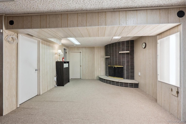 unfurnished living room featuring a brick fireplace, wooden walls, and carpet floors