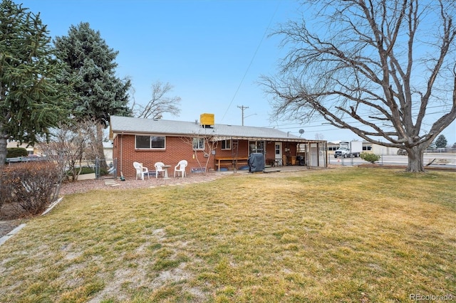 back of property featuring fence, brick siding, a lawn, and a patio area