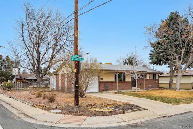 ranch-style home featuring brick siding, fence, concrete driveway, a front yard, and an attached garage