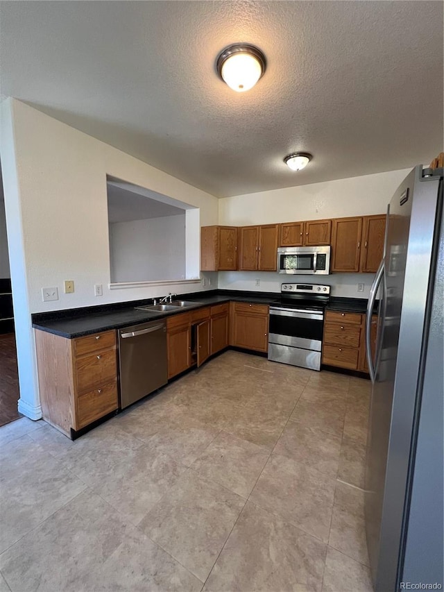 kitchen featuring a textured ceiling, stainless steel appliances, and sink