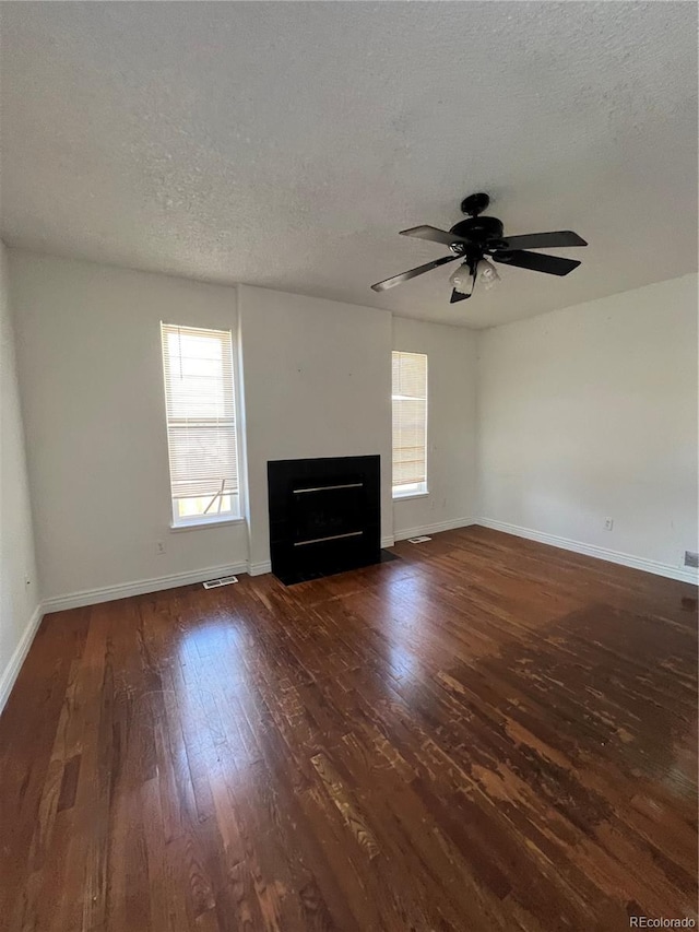 unfurnished living room featuring ceiling fan, a textured ceiling, and dark hardwood / wood-style flooring