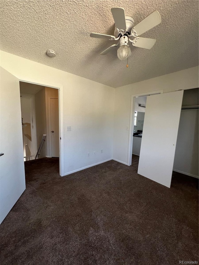 unfurnished bedroom with dark carpet, a textured ceiling, and ceiling fan