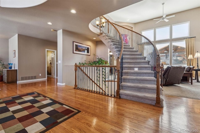 staircase featuring hardwood / wood-style floors and ceiling fan with notable chandelier