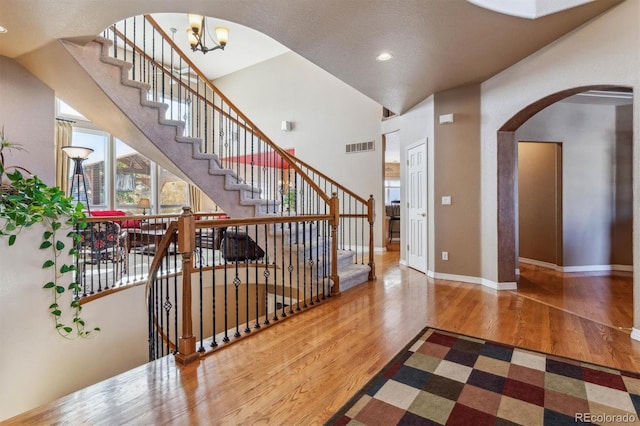 interior space with a textured ceiling, hardwood / wood-style flooring, high vaulted ceiling, and an inviting chandelier