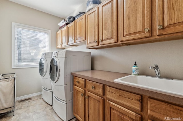 clothes washing area with washer and clothes dryer, cabinets, and sink