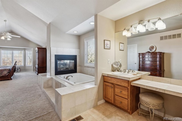 bathroom with a tile fireplace, ceiling fan, tile patterned flooring, lofted ceiling, and vanity