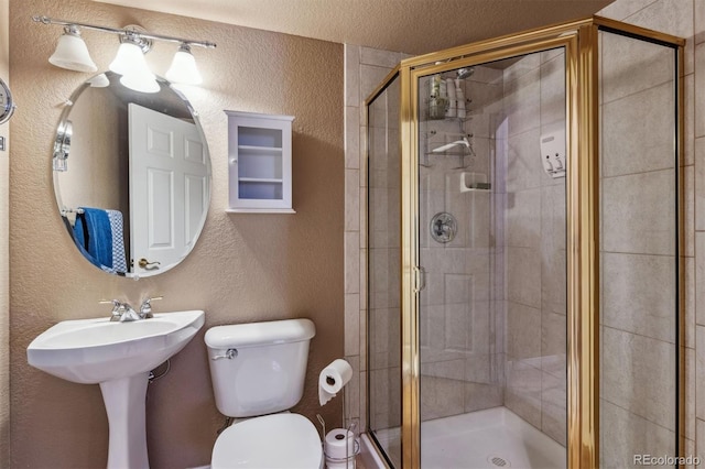 bathroom with a textured ceiling, sink, an enclosed shower, and toilet