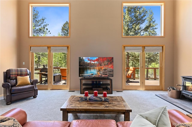 carpeted living room with a wood stove and a towering ceiling