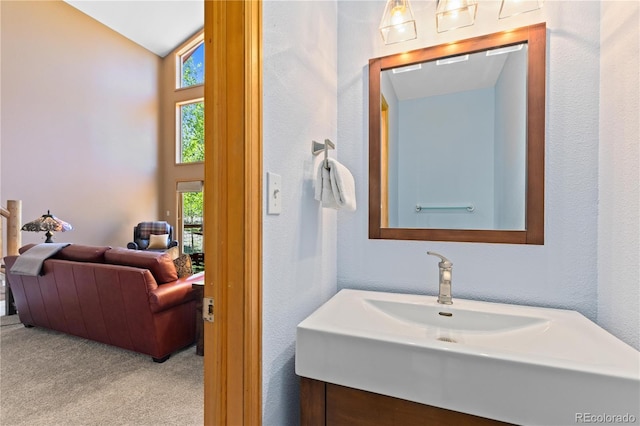 bathroom featuring lofted ceiling, a textured wall, and a sink