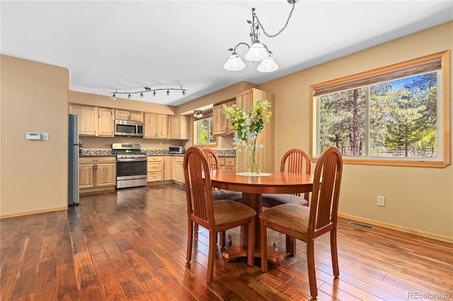 dining space with visible vents, dark wood finished floors, baseboards, and an inviting chandelier