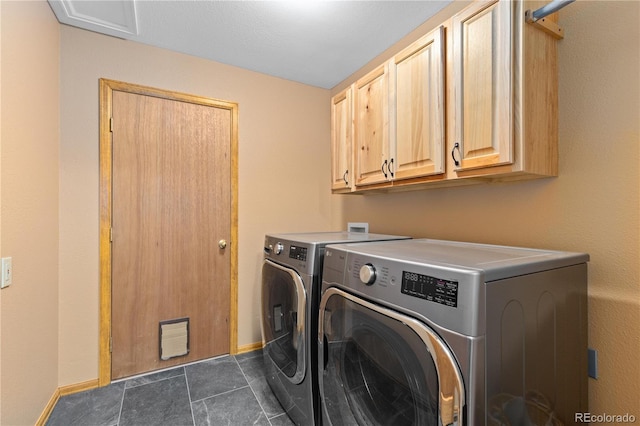 laundry area with cabinet space, baseboards, washer and clothes dryer, and dark tile patterned flooring