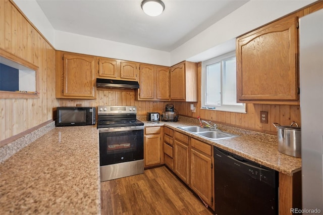 6545 Brook Forest Dr, Colorado Springs, CO 80911 - kitchen featuring black appliances, under cabinet range hood, light countertops, wood walls, and dark wood-style floors