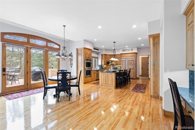 dining space featuring light wood-type flooring and an inviting chandelier