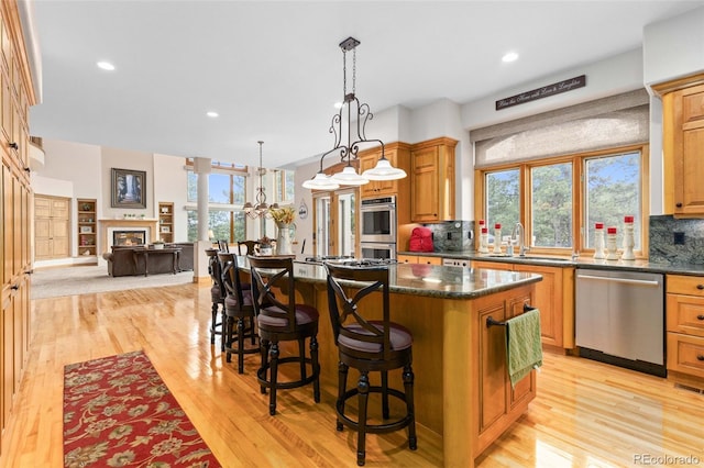 kitchen featuring appliances with stainless steel finishes, sink, a center island, decorative light fixtures, and tasteful backsplash