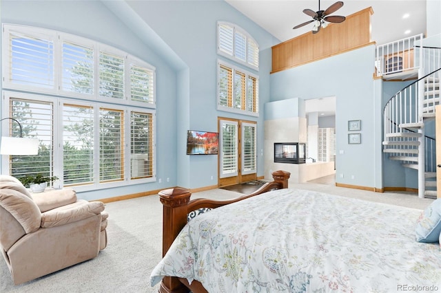 carpeted bedroom featuring multiple windows, a fireplace, and a towering ceiling