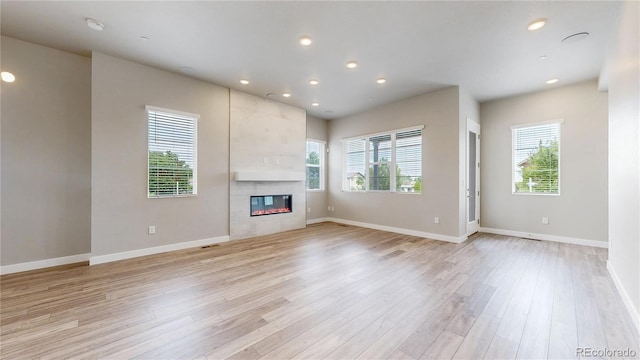 6799 Navajo St, Denver, CO 80221 - unfurnished living room featuring light wood-type flooring, a tiled fireplace, and recessed lighting