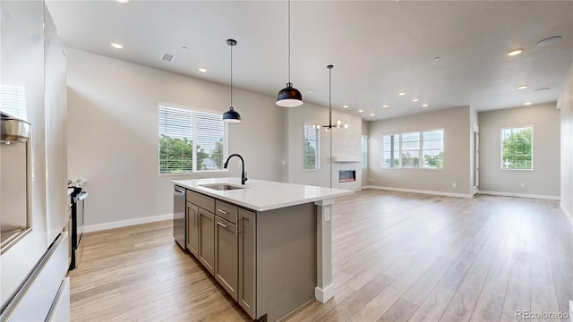6799 Navajo St, Denver, CO 80221 - kitchen featuring gray cabinetry, appliances with stainless steel finishes, light wood-style flooring, a kitchen island with sink, and recessed lighting
