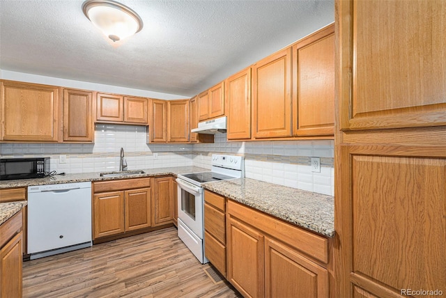 2308 Lima St, Aurora, CO 80010 - kitchen with white appliances, under cabinet range hood, decorative backsplash, light wood-style floors, and light stone counters