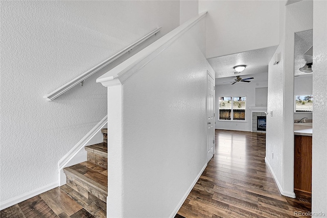 hall featuring stairway, baseboards, wood finished floors, and a textured wall