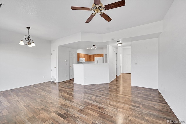 unfurnished living room featuring visible vents, ceiling fan with notable chandelier, baseboards, and wood finished floors