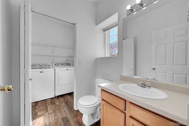 bathroom with vanity, wood finished floors, toilet, and washing machine and dryer