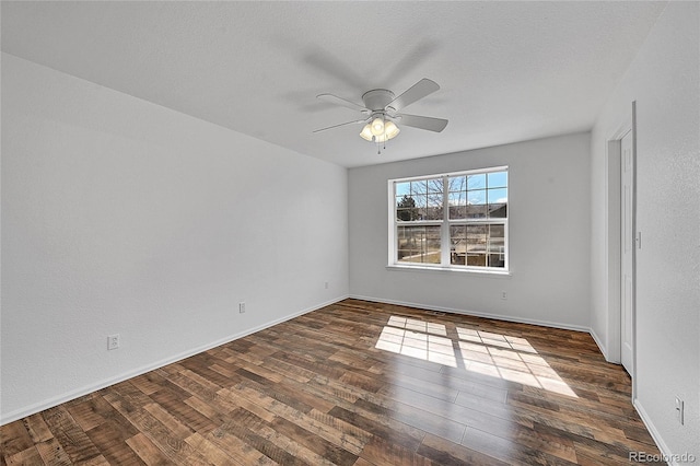 empty room featuring dark wood-type flooring, baseboards, and ceiling fan