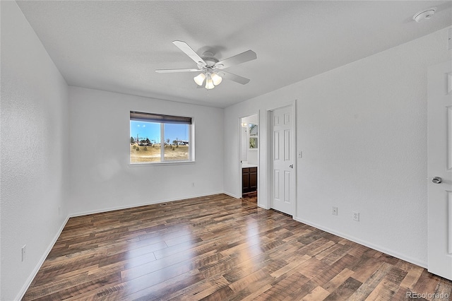 unfurnished bedroom with a ceiling fan, ensuite bathroom, baseboards, and wood finished floors