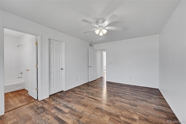 unfurnished bedroom with visible vents, ensuite bath, wood finished floors, baseboards, and ceiling fan