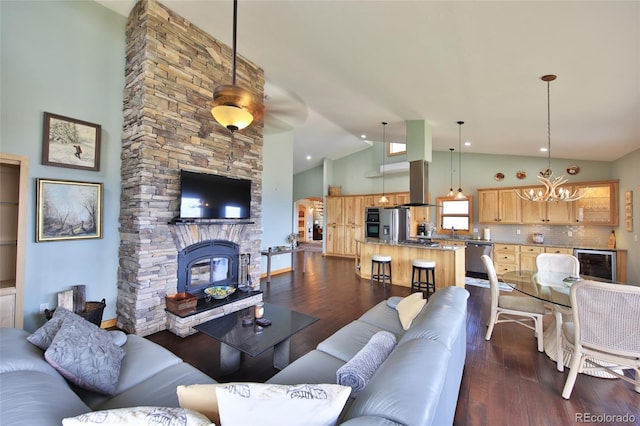 53315 Bull Basin Rd, Mesa, CO 81643 - living room featuring beverage cooler, a chandelier, dark wood finished floors, high vaulted ceiling, and a stone fireplace