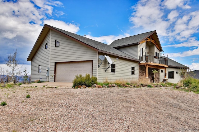 53315 Bull Basin Rd, Mesa, CO 81643 - view of side of property with dirt driveway, a balcony, a garage, and a shingled roof