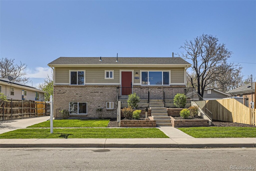 6488 E 63rd Pl, Commerce City, CO 80022 - view of front facade featuring brick siding, fence, and a front yard
