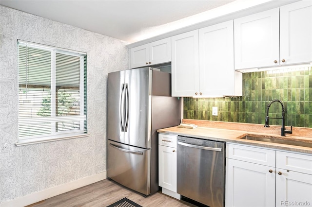 1749 Havana St, Aurora, CO 80010 - kitchen featuring appliances with stainless steel finishes, a sink, light wood-style flooring, light countertops, and white cabinets