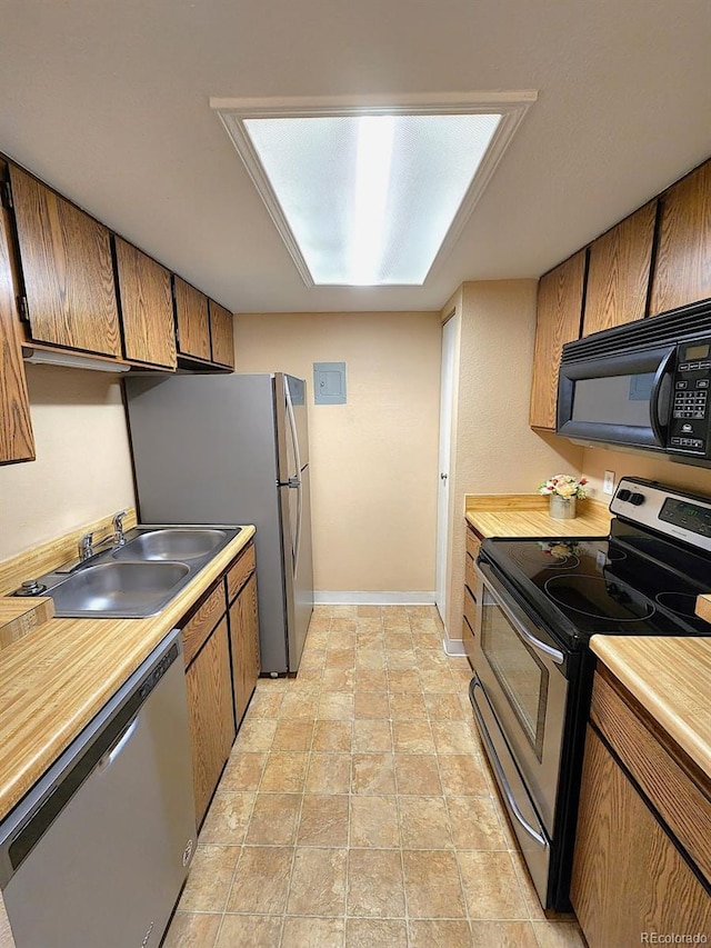 kitchen featuring stainless steel appliances, brown cabinetry, a sink, and light countertops